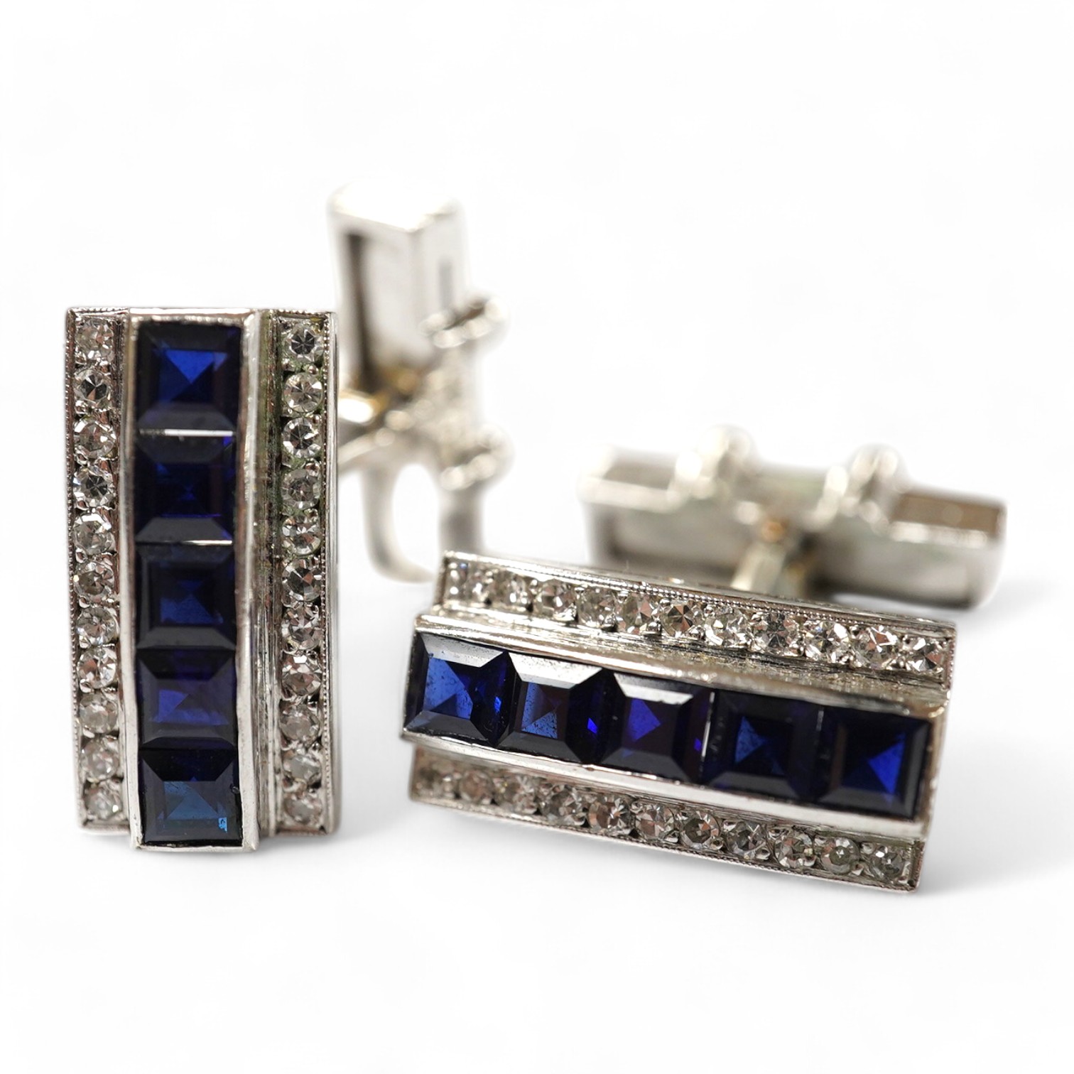 A pair of white metal, synthetic sapphire and diamond three row line cuff links, of curved rectangular form, 18mm, gross weight 16.6 grams. Condition - fair to good